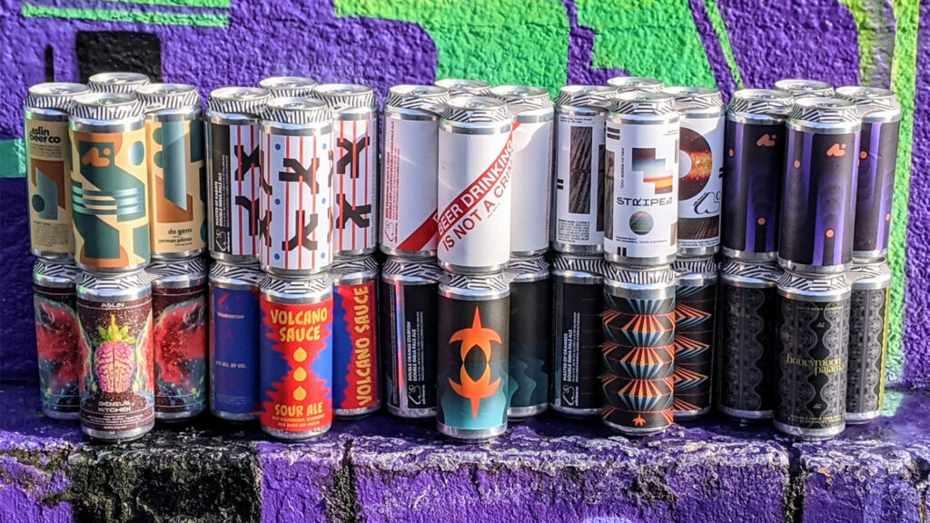 A collection of various Aslin Brewery custom designed been cans stacked in a group.
